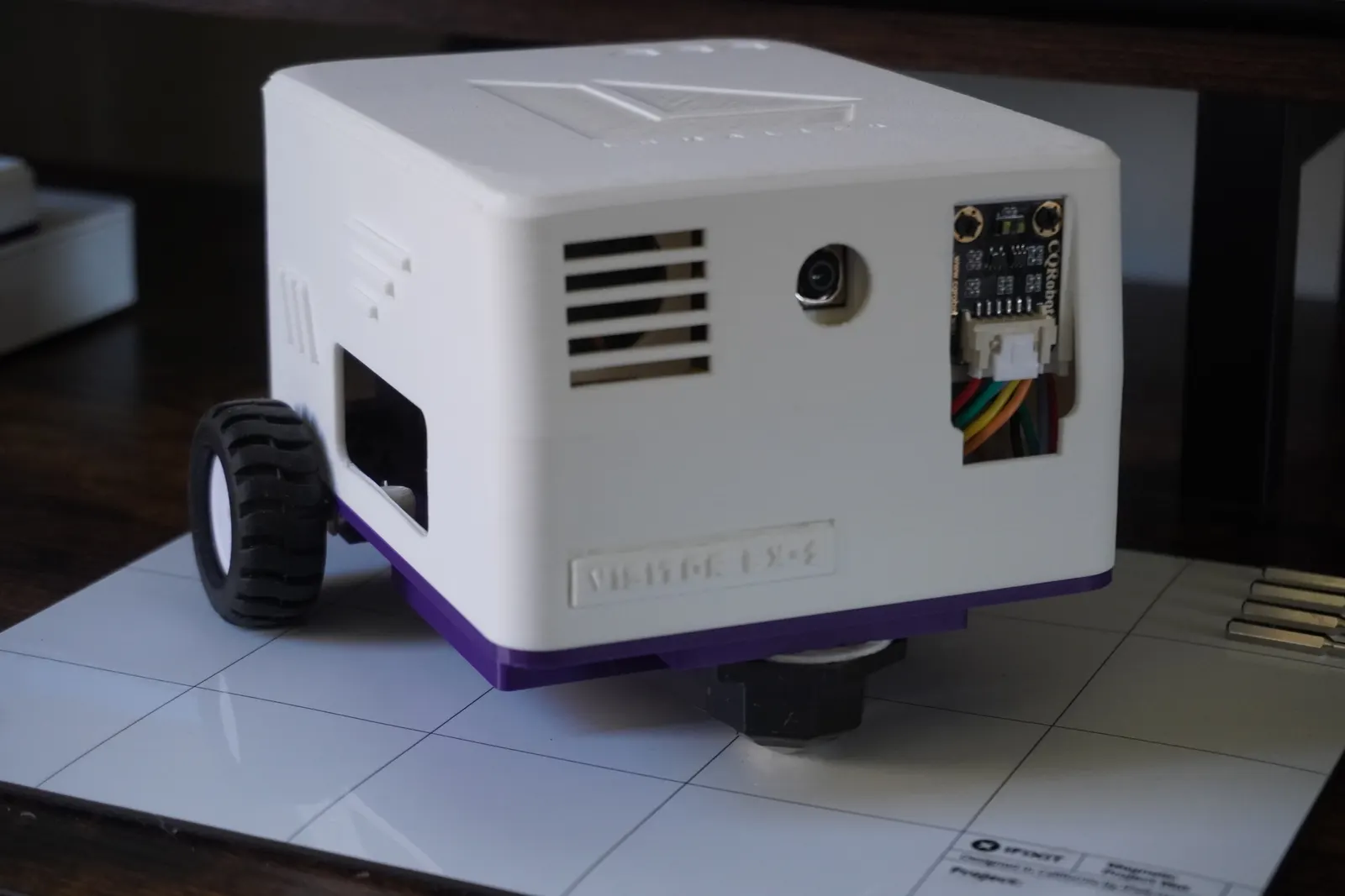 VISITOR LX-1 on a white mat: a white printed shell on a purple chassis, with its camera and distance sensor on the front